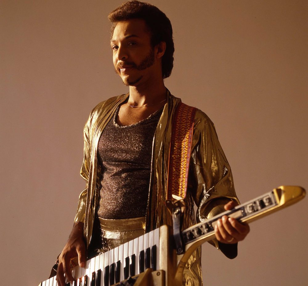 A man in gold jacket holding a guitar.